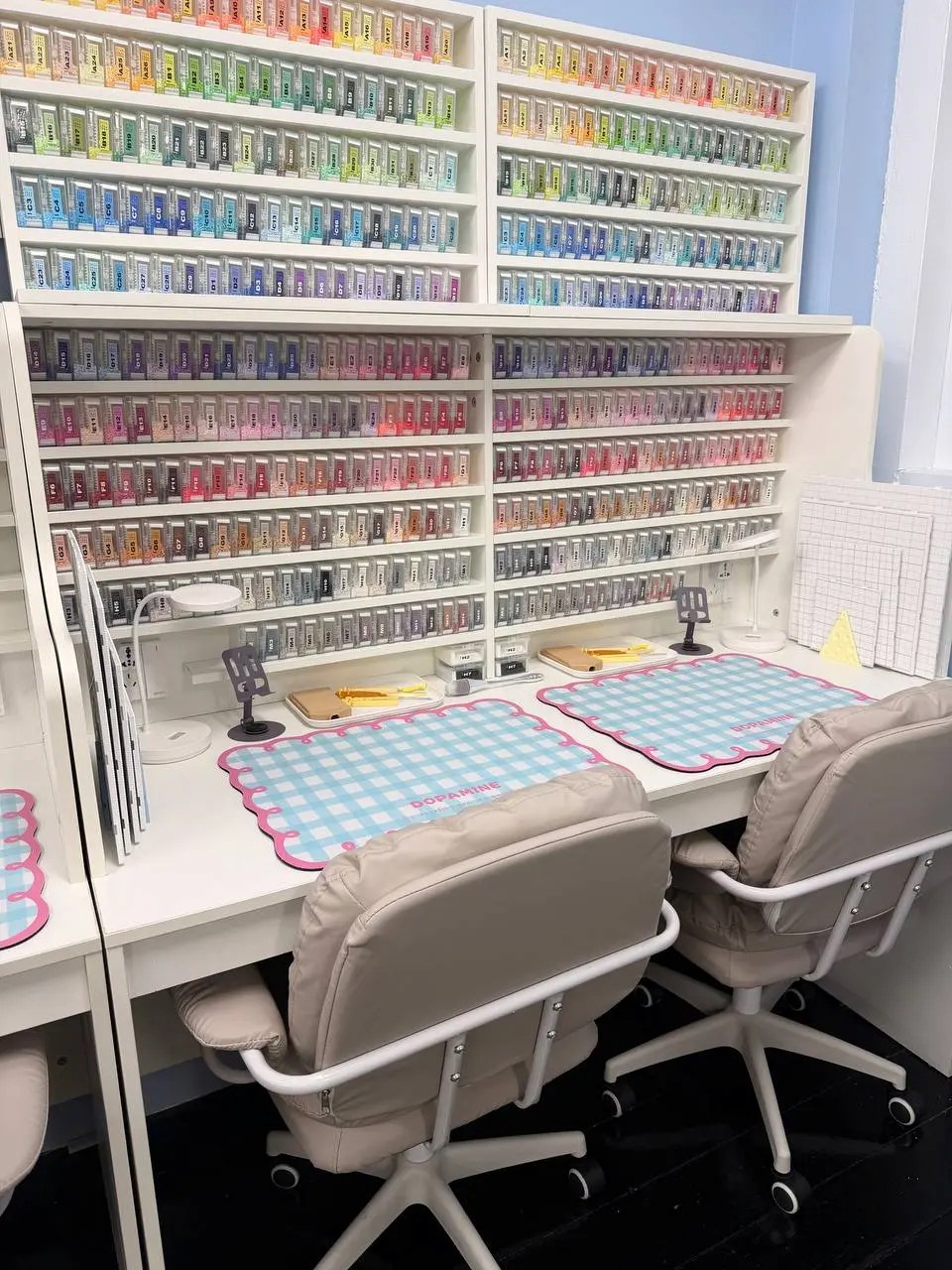 Two beading desks side by side under shelves of bead colours, a chair at each