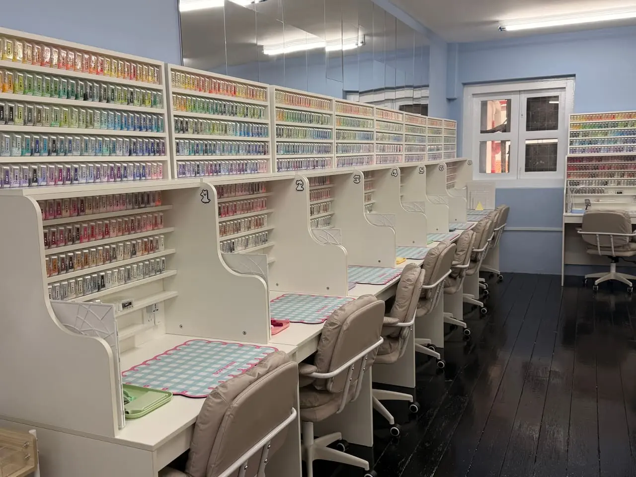 A row of single beading desks, each with a gingham mat and its own shelves of bead colours